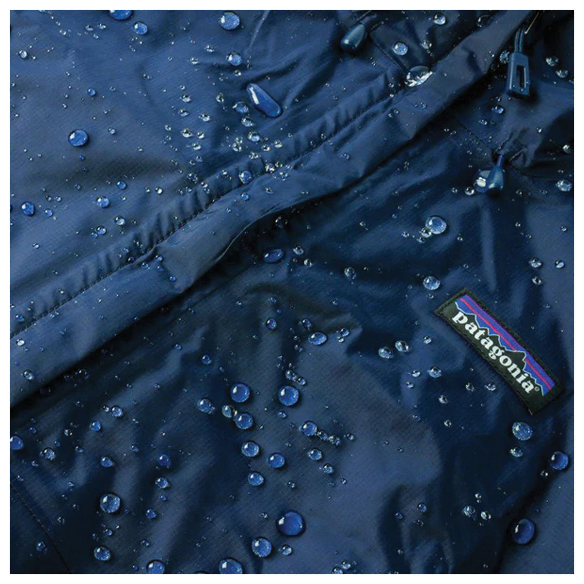 Water droplets on blue jacket fabric beside a zipper