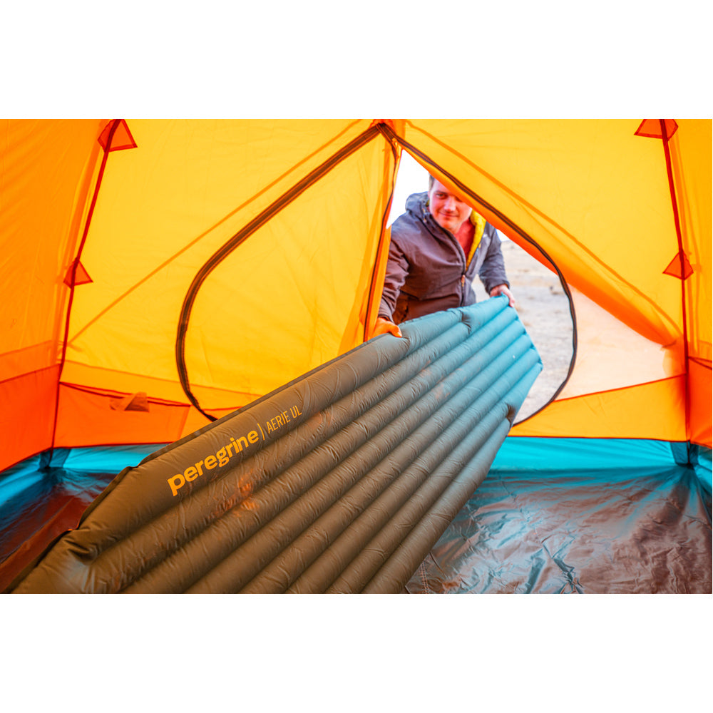 Camper placing a Peregrine Aerie UL air pad inside a tent