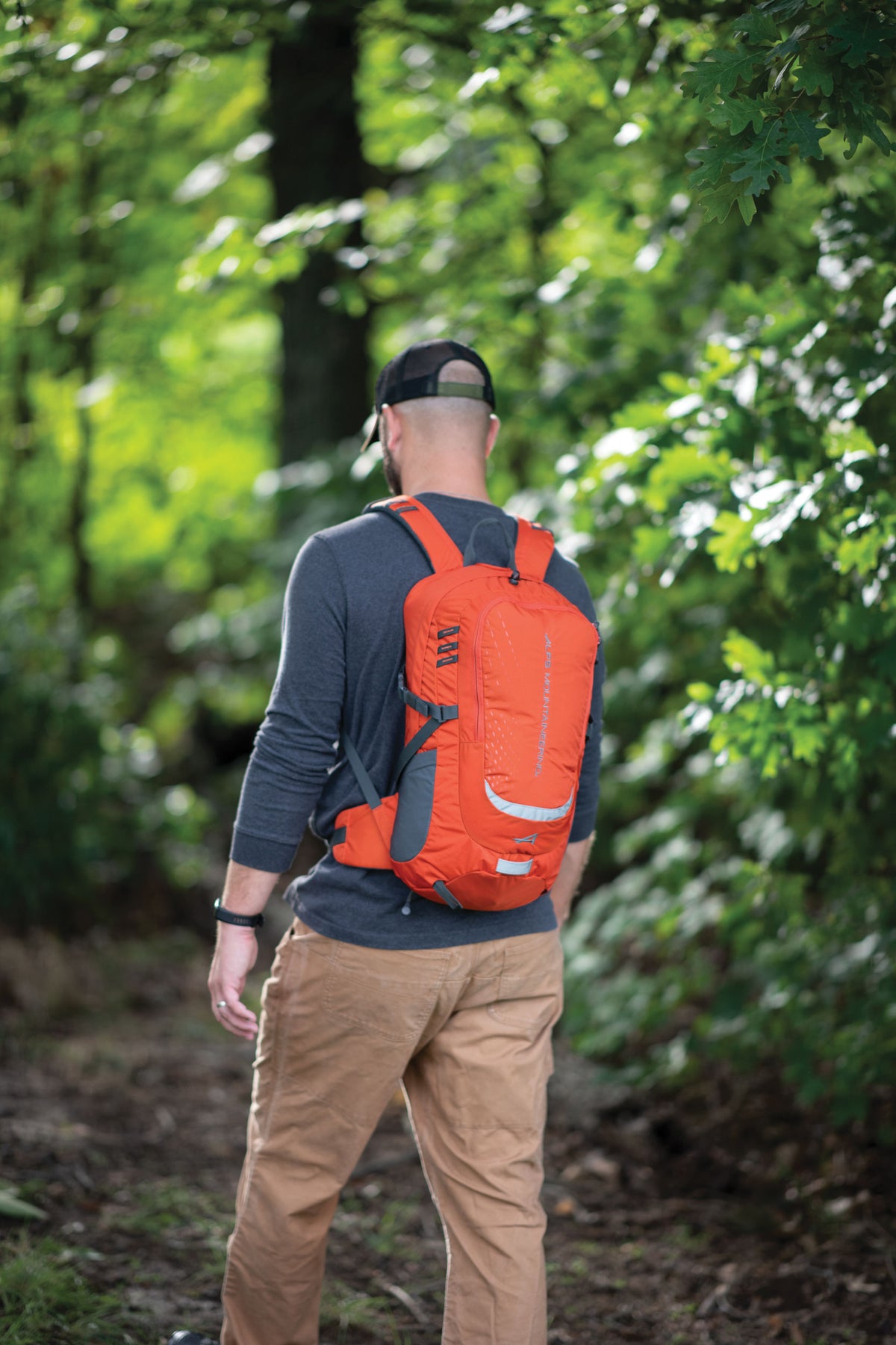 Hiker wearing the Chili ALPS Mountaineering Hydro Trail 17L pack on a wooded trail