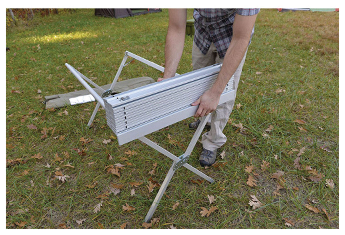 Camper lifting a folded roll-top from an ALPS aluminum dining table frame