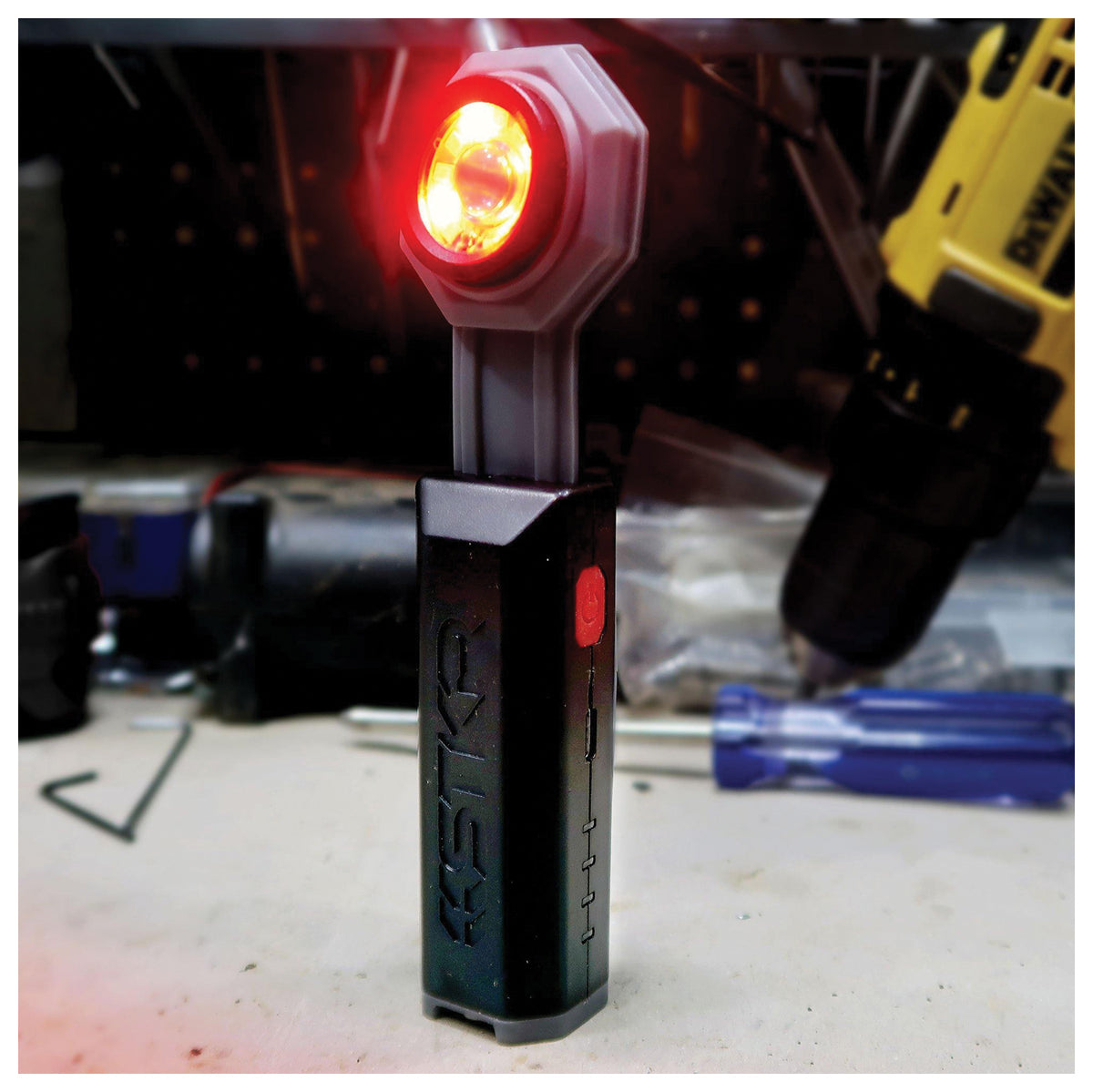 STKR FLEXIT Pocket Light 4.0 standing on a workbench with its red light illuminated