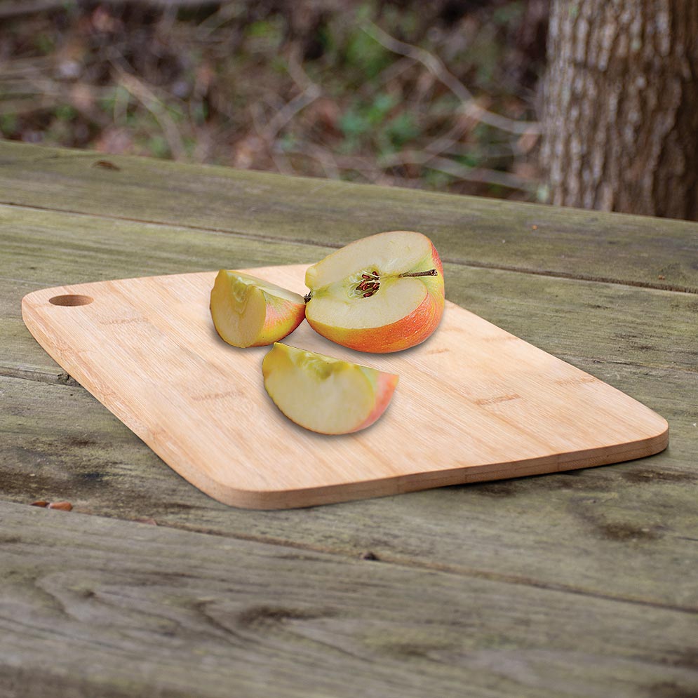 UST Bamboo Cutting Board 2.0 with sliced apple on a picnic table