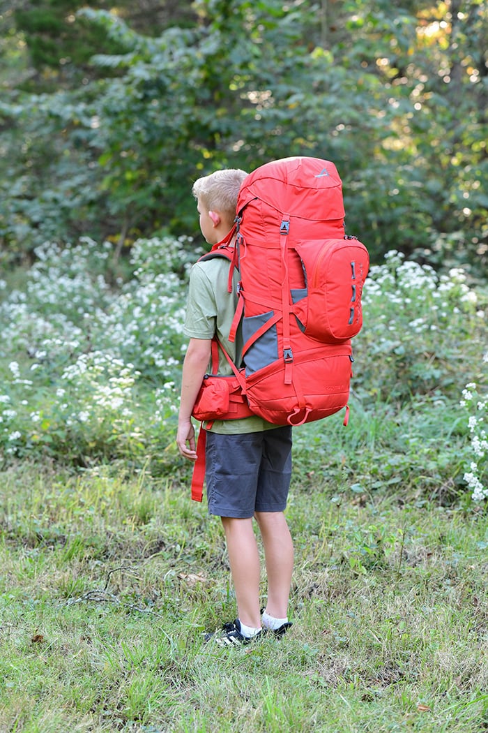 Side view of a hiker wearing a Chili Red Tail 65L pack