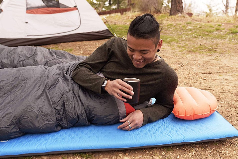 Camper resting on a blue ALPS Flexcore sleeping pad