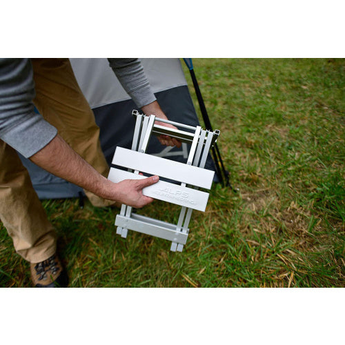 Camper folding a silver ALPS SideKick for carrying