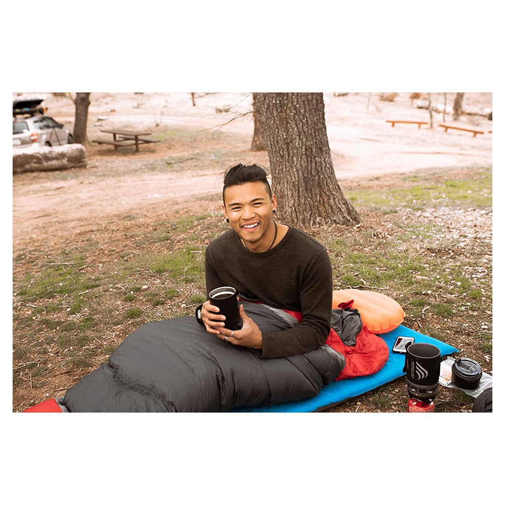 Camper sitting in a sleeping bag with an orange ALPS Versa pillow