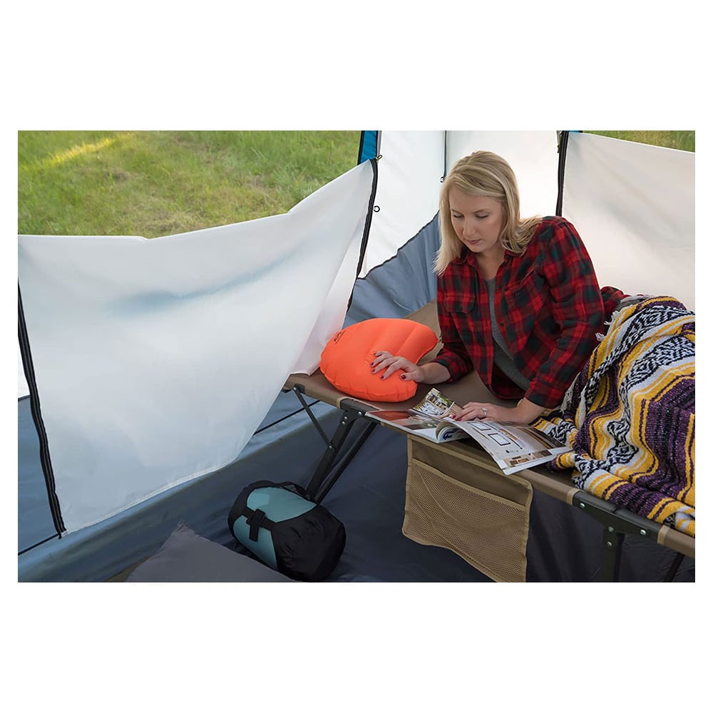 Camper beside an orange ALPS Versa pillow on a cot inside a tent