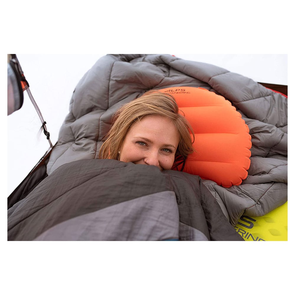 Camper resting on an orange ALPS Versa pillow in a sleeping bag