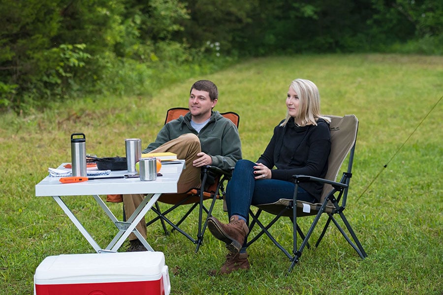 Campers relaxing beside an ALPS aluminum dining table on grass