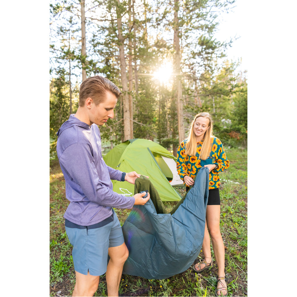Campers connecting Peregrine Link-Up field quilts at a wooded campsite
