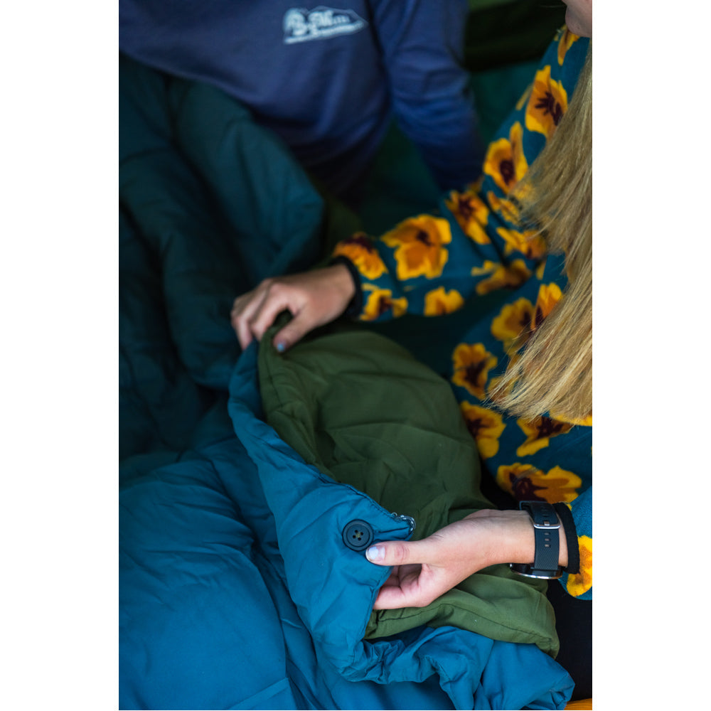 Close-up of hands fastening two Peregrine Link-Up field quilts together