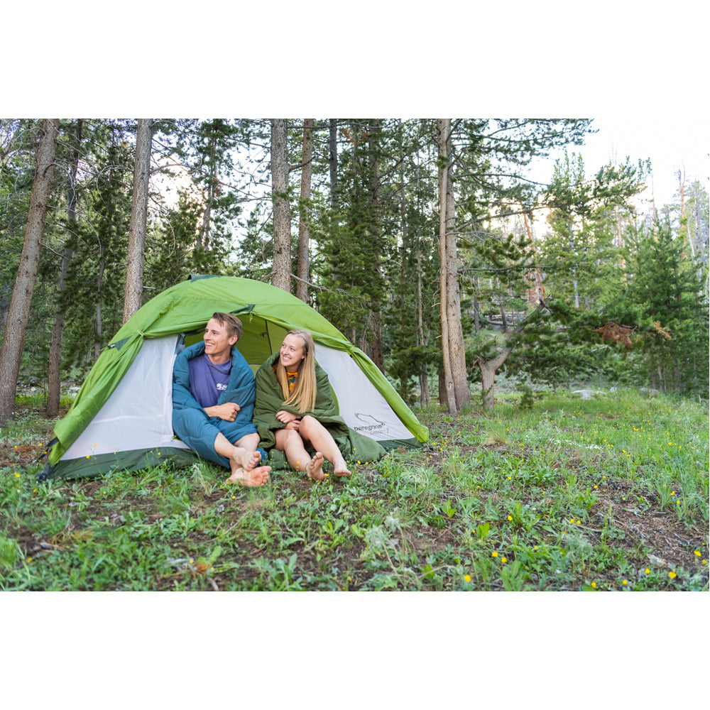 Campers seated at a tent entrance with Peregrine Link-Up field quilts