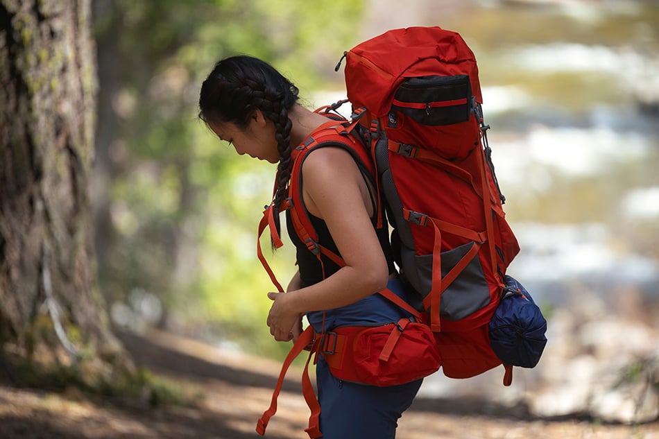 Hiker wearing a Chili Red Tail 65L pack with gear secured around the outside