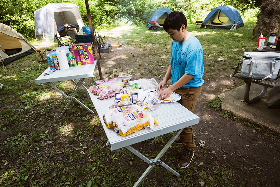 ALPS aluminum dining table used to organize food at a wooded campsite