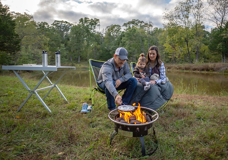 ALPS Square Dining Table beside campers and a fire pit near a pond