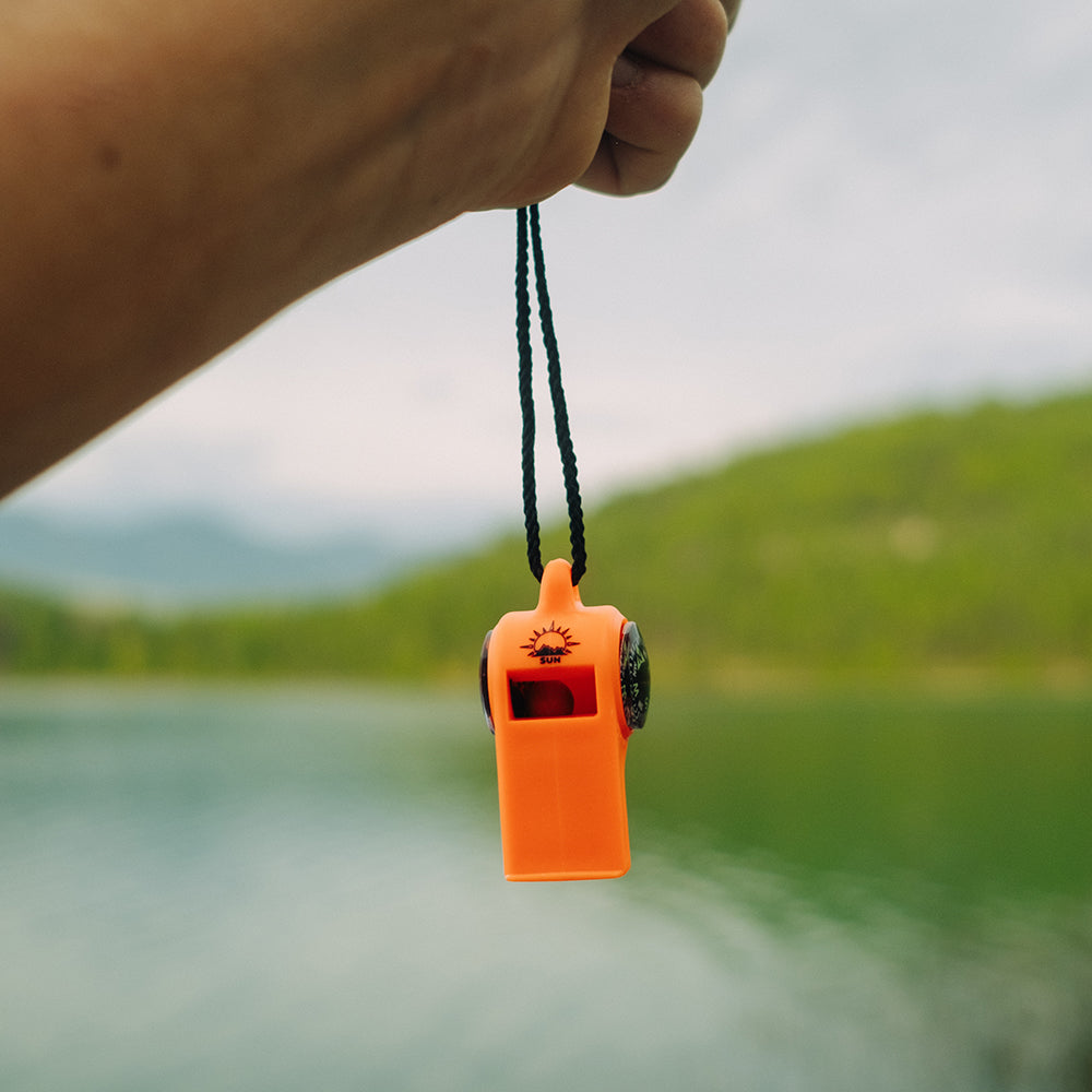 Orange Sun Company TripleWhistle hanging from its black lanyard outdoors