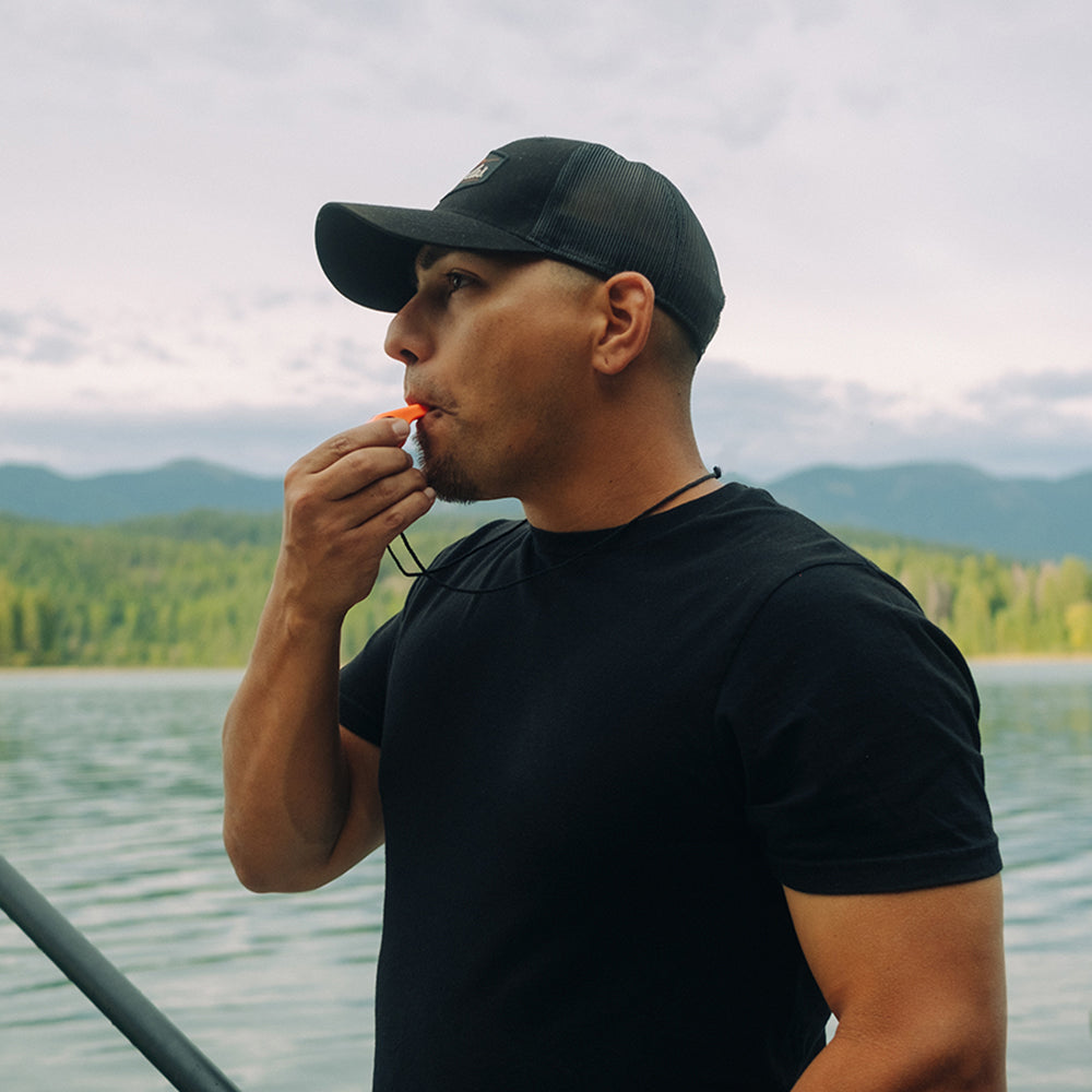 Person using the orange Sun Company TripleWhistle outdoors