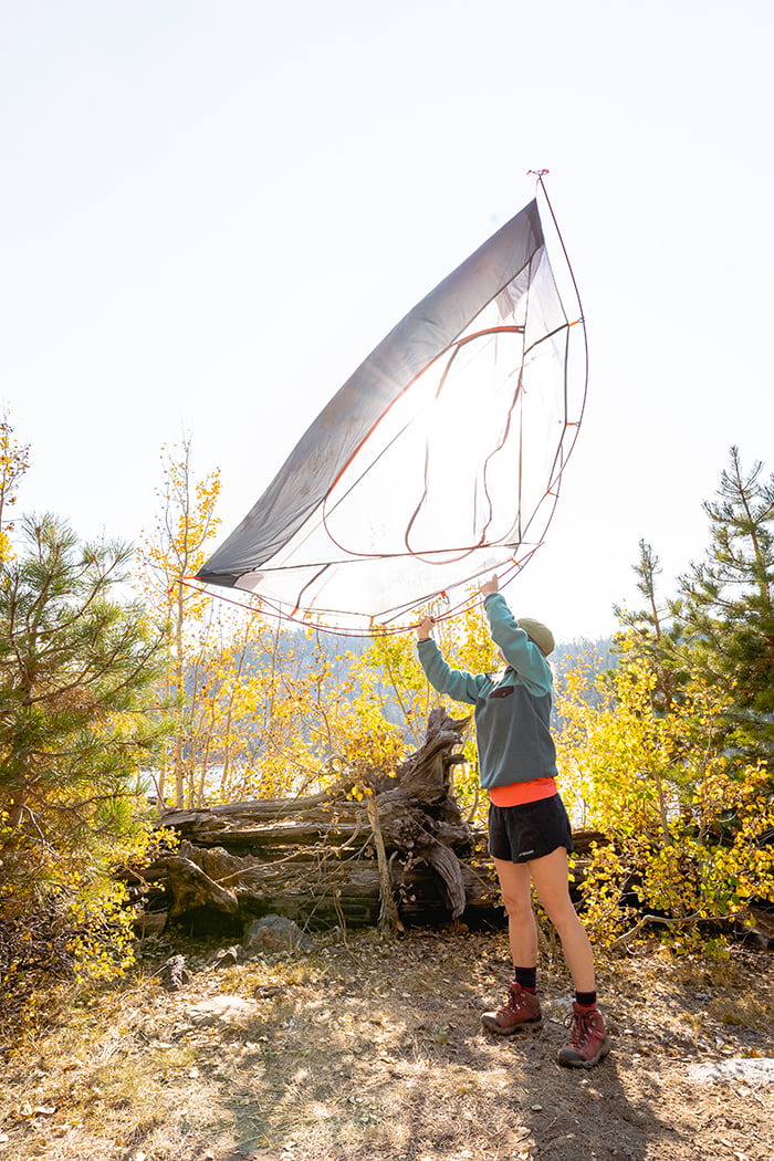 Camper lifting an ALPS Helix mesh tent body outdoors