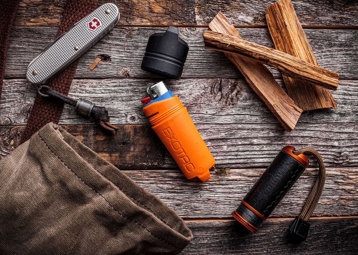 Orange Exotac fireSLEEVE lighter case shown with fire-starting gear