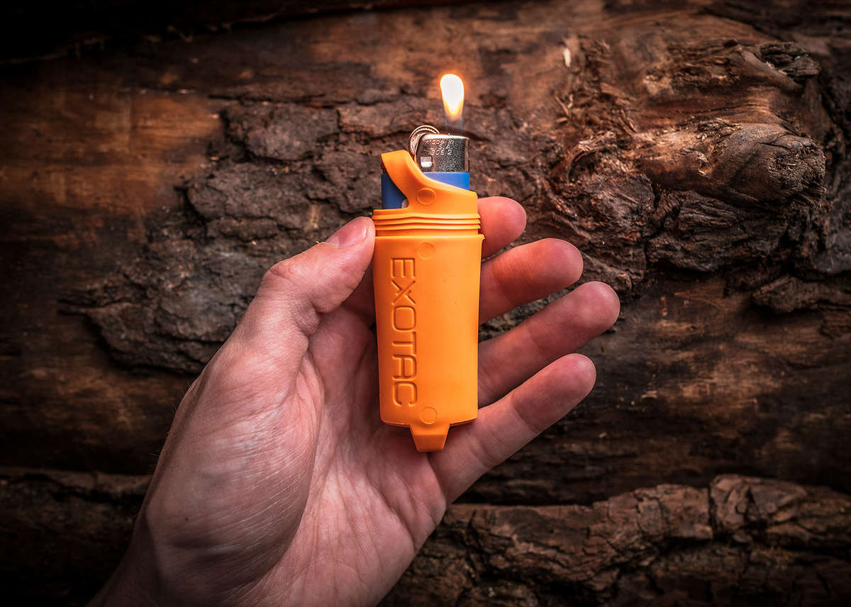 Hand holding an orange Exotac fireSLEEVE lighter case